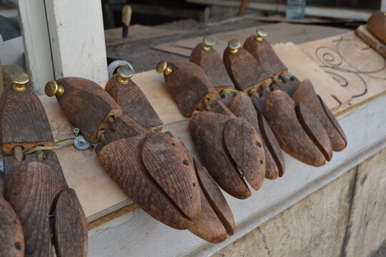 Row of vintage wooden shoe lasts and cobbler forms on bench for shoemaking background and craft workshop display