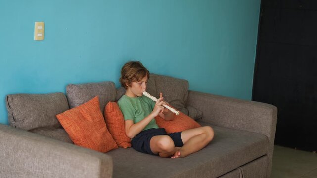 A little boy learns to play the flute at home, practicing with focus and enthusiasm in a cozy, warm setting. A charming scene of early musical exploration, creativity, and childhood growth.