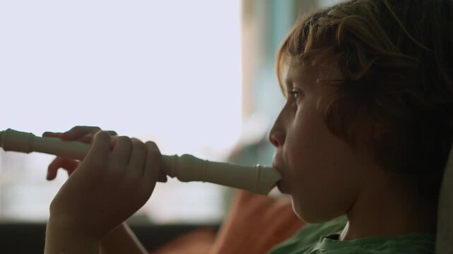 A little boy learns to play the flute at home, practicing with focus and enthusiasm in a cozy, warm setting. A charming scene of early musical exploration, creativity, and childhood growth.