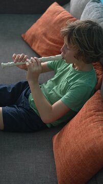 A little boy learns to play the flute at home, practicing with focus and enthusiasm in a cozy, warm setting. A charming scene of early musical exploration, creativity, and childhood growth.