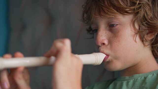 A little boy learns to play the flute at home, practicing with focus and enthusiasm in a cozy, warm setting. A charming scene of early musical exploration, creativity, and childhood growth.