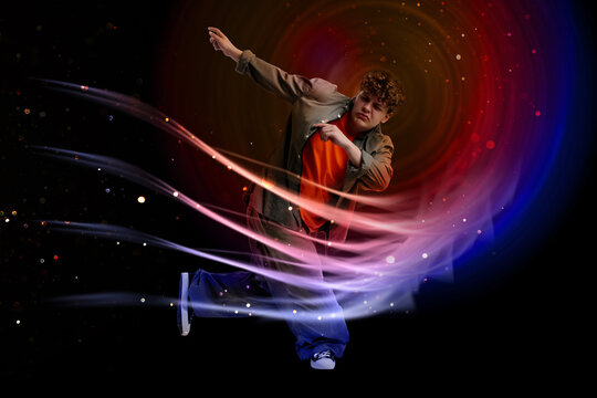 Young hip-hop dancer posing in bright lights against dark background. Creative poster