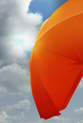 Orange sun umbrella against blue sky with fluffy clouds. Summer season © New Africa
