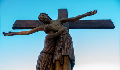 A wooden statue of the Deposition of Christ stands under the open sky. © Joan