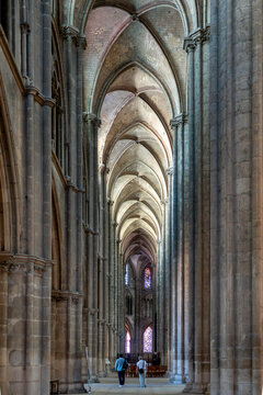 Two visitors walking in Gothic Cathedral Aisle.