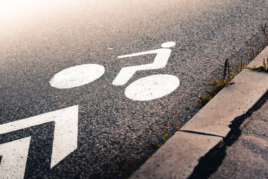 White bicycle lane sign painted on asphalt road surface at sunset