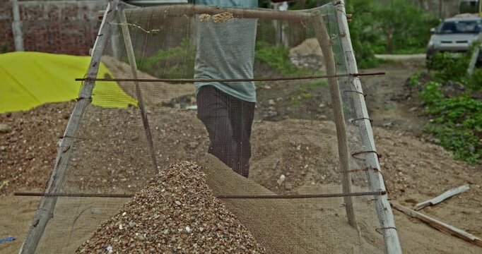 Construction Laborers Preparing Sand at an Indian Building Site Using a Handheld Metal Sieve. Skilled manual workers perform traditional sand screening work during ongoing construction activities