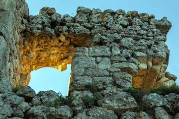 Stone ruins stand in sunlight under a clear blue sky at a historical site © photosaint