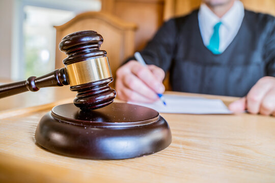 Judge Writing Notes Beside Gavel and Sound Block in Courtroom