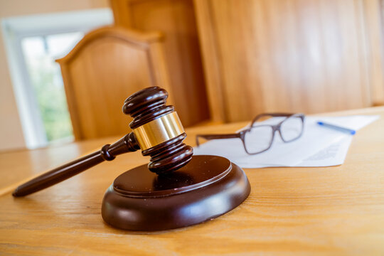 Judge's Gavel with Glasses and Documents on Courtroom Desk