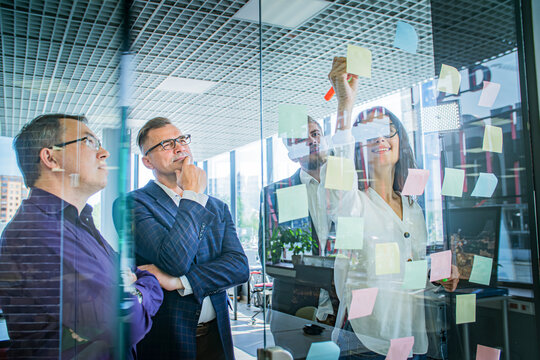 Business Team Brainstorming with Sticky Notes on Glass Wall