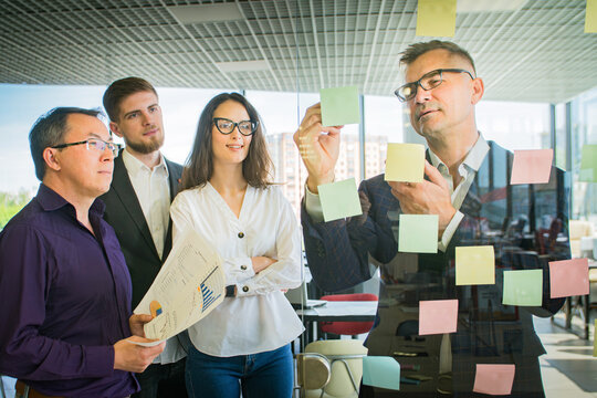 Business Team Brainstorming with Sticky Notes on Glass Wall