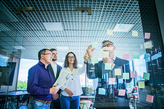 Business Team Brainstorming with Sticky Notes on Glass Wall