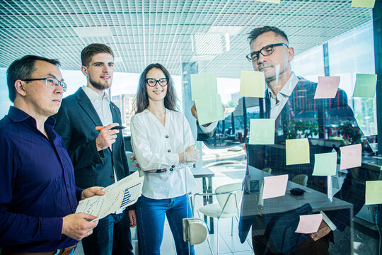 Business Team Brainstorming with Sticky Notes on Glass Wall