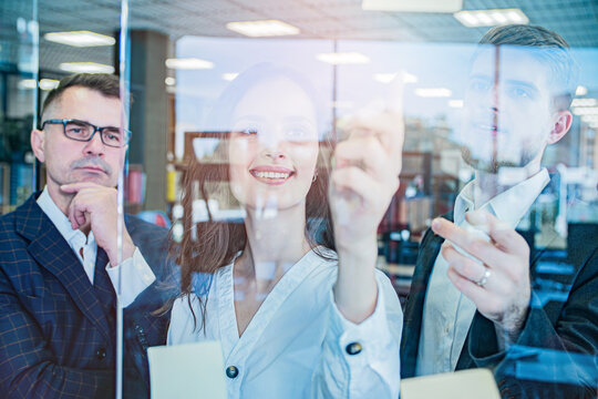 Business Team Writing Ideas on Glass Board Through Reflection