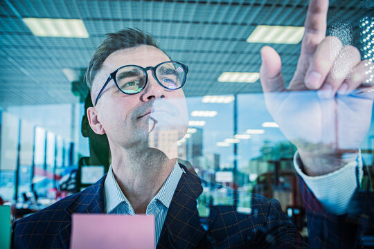 Businessman Touching Virtual Screen with Finger in Modern Office