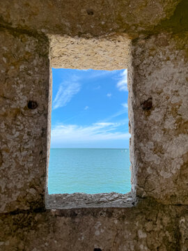 stone window frames a sunny view of blue sea and sky