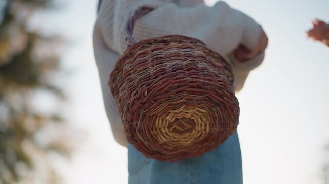 Close up of woman carrying woven basket on her back with another woman partially visible. focus remains consistently on detailed texture and pattern of wicker material. Soft sunlight creates
