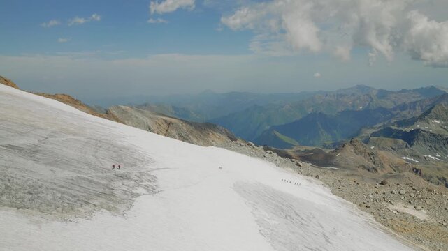 Alpinists crossing glacier captured from the top of the mountain in Italian alps