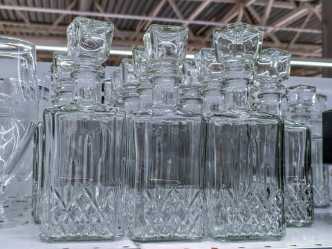 Crystal glass decanter standing on retail store shelf. Clear liquor bottle with stopper for home bar and beverage serving. Kitchenware shopping in supermarket for interior decoration