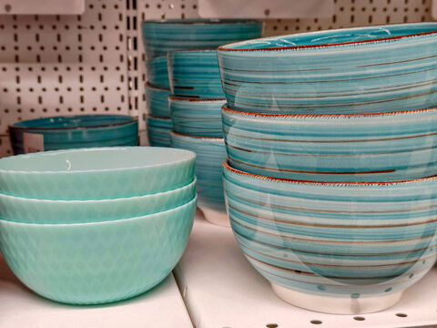Stack of blue ceramic bowls on a retail supermarket shelf. Modern kitchenware collection for dining and home decor. Display of tableware in a store for shopping and cooking interior