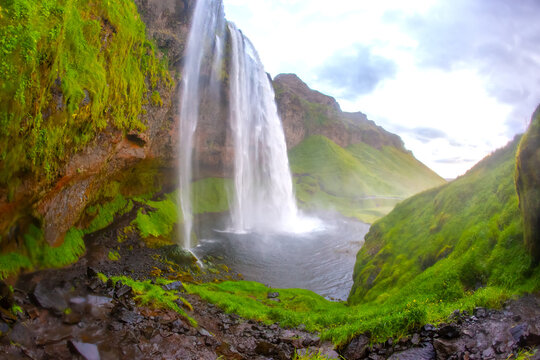 Seljalandsfoss waterfall in Iceland with green hills and flowing water during daylight