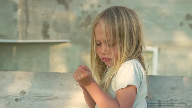 Boy examining his hand closely looking for a splinter in golden hour close-up