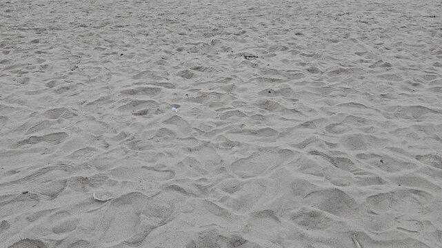 white sand texture,Fine sand stretches across the scene. Footprints mark the surface with gentle curves. Footsteps suggest recent passage or lingering traces. The sand holds quiet, untouched beauty