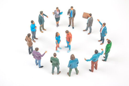 Miniature figures in a circle discussing ideas in a bright setting