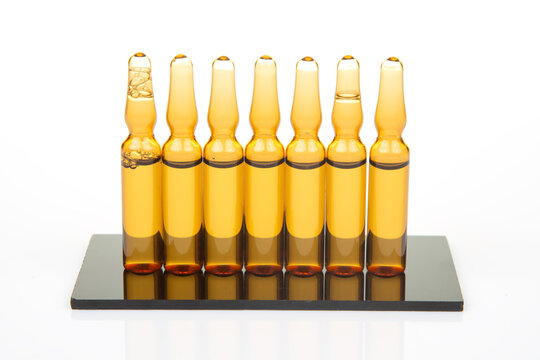 Collection of glass vials arranged on a black base with an empty space at the left side showing clear liquid