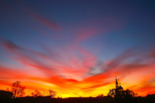 Sunset over the city with silhouettes of trees and buildings in the background