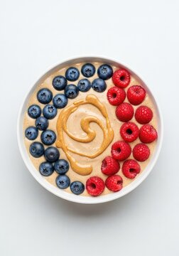 Top view of a delicious banana and almond butter smoothie bowl garnished with fresh blueberries and raspberries for a healthy snack, ingredients, natural, superfood
