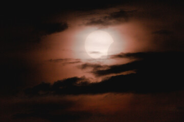 Fototapeta premium Partial Solar Eclipse in Dark Cloudy Sky, White Sun Initial Phase