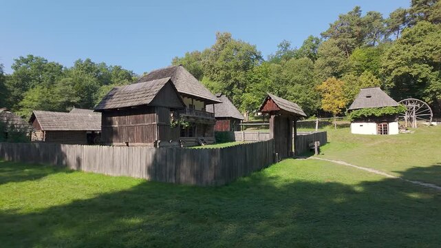 Traditional Romanian wooden farmhouse complex with fenced yard and old water wheel