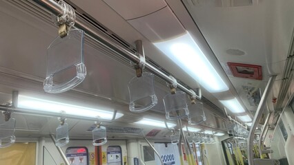 Transparent hand grips suspended inside a modern commuter train, providing passenger support during public transportation travel © MR HEPPY