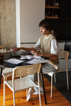 Young concentrated woman paying with credit card on laptop at desk