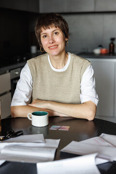 Smiling woman at desk with cup of tea, cut credit card and documents