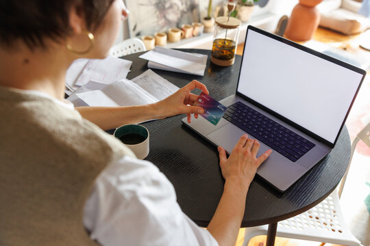 Partial woman paying with credit card on laptop computer at desk