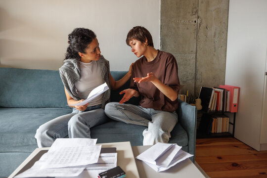 Woman soothing embarrassed girlfriend while they reviewing bills