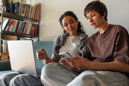 Focused women paying for bills and taxes with mobile app and laptop