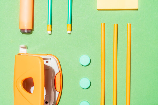 Colorful office supplies arranged on green background