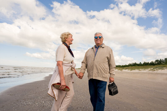 Senior Couple Walks on the Beach Holding Hands