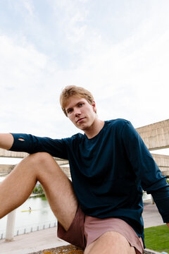 Athletic man posing confidently on a park railing in sportswear