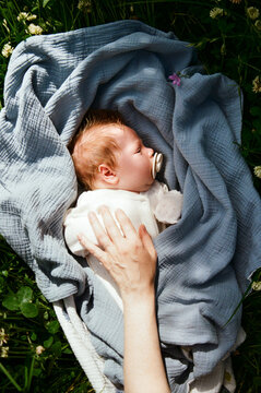 Baby resting on grass with blanket and hand