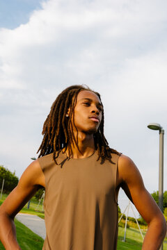 Medium shot of confident Black elite athlete with dreadlocks at dawn