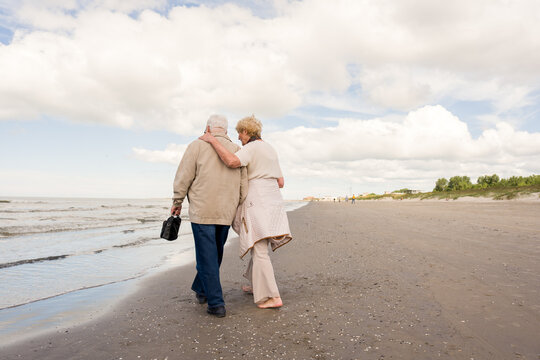 Senior Couple Walks Along the Beach by the Water