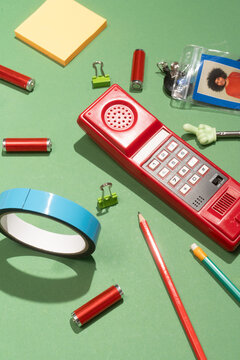 Retro red cordless phone with colorful office supplies flat lay