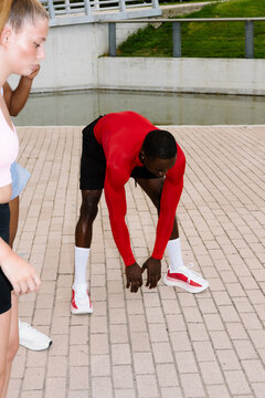 Athletic black man doing stretching exercises before starting to run