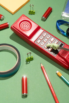 Retro red telephone with office supplies on green background
