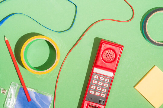 Retro red telephone with office supplies on green background